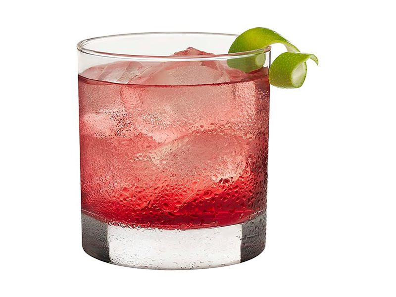 Red cocktail with lime twist garnish